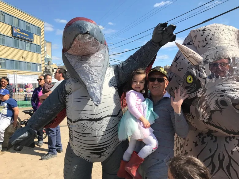 Addison Tsang introduces his granddaughter Stella to some dinosaurs who were out celebrating Nunavut Day. (Sara Frizzell/CBC)