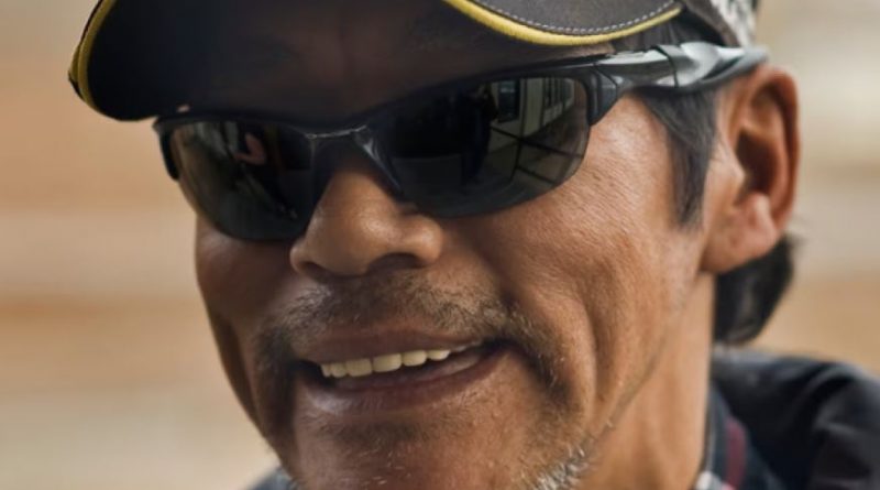 A man wearing sunglasses smiles