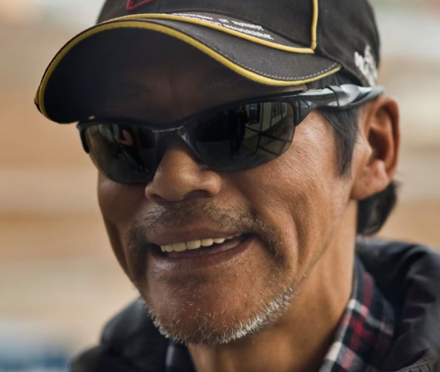 A man wearing sunglasses smiles
