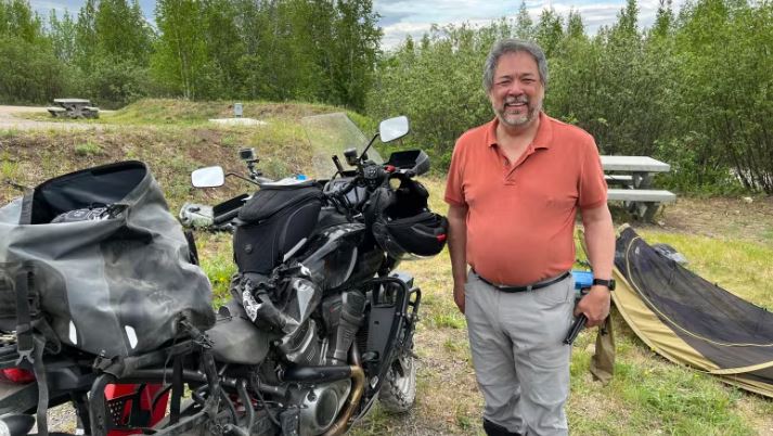 A man stands next to his motorcycle.