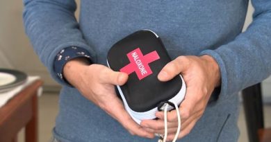 Male hands holding a small black case with a white zipper going around it.