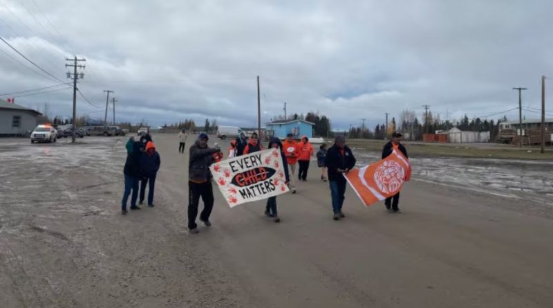 People walking wearing orange shirts and carrying handpainted signs saying every child matters