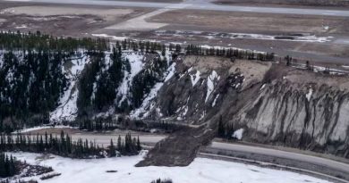A aerial view of a landslide with debris blocking off a road.