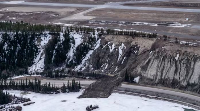 A aerial view of a landslide with debris blocking off a road.