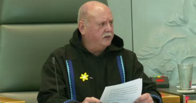 Man sits with papers in hand.