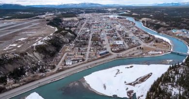 An aerial view of buildings by a river An aerial view of downtown Whitehorse.