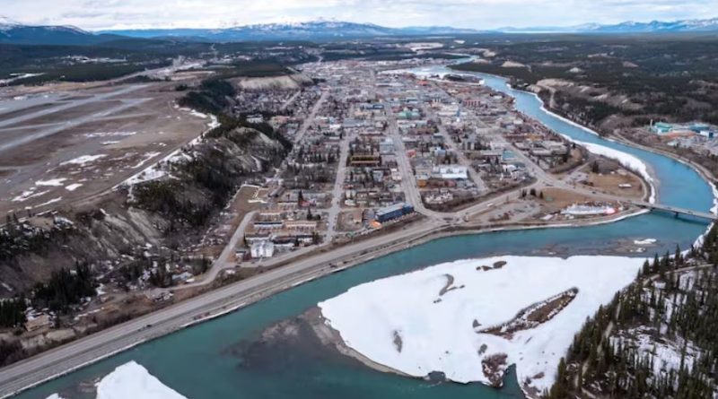 An aerial view of buildings by a river An aerial view of downtown Whitehorse.