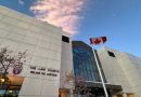 An off-white building with a large multi-story glass window. A sign on the building says "THE LAW COURTS." And Canadian flag is out front.