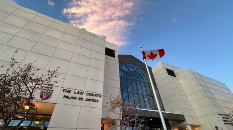 An off-white building with a large multi-story glass window. A sign on the building says "THE LAW COURTS." And Canadian flag is out front.