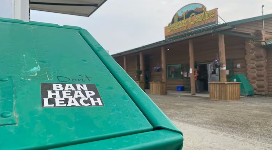 A sticker on a garbage can outside of a rural store reads, 'Ban heap leach.'