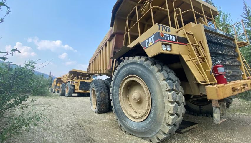 A line of big dump trucks on a gravel road.