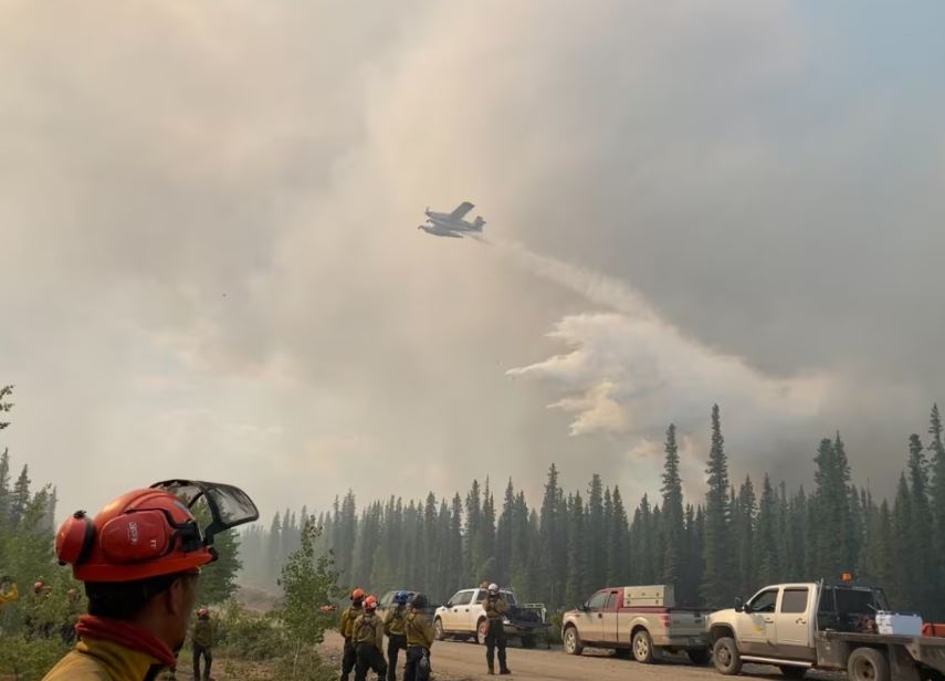 Firefighters look at smoke and water falling.