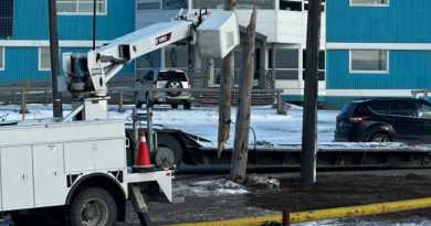 A machine near a broken power pole in front of a blue building.