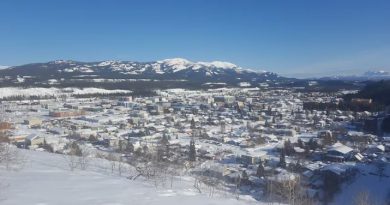 Overlooking a small city in winter, with mountains in the background.
