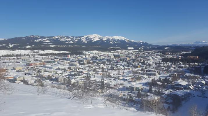 Overlooking a small city in winter, with mountains in the background.
