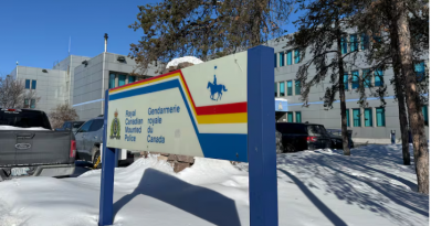 A blue, red and white sign on a sunny day, winter day, outside a building.