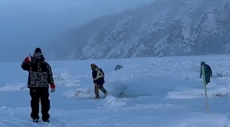 A group of people in snowsuits. One person is giving a thumbs up.