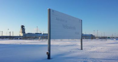 A large sign in the snow with a large building in the background.
