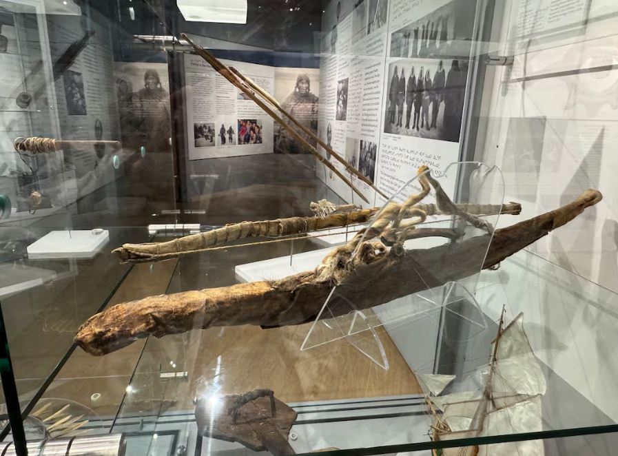 an old brown bow and arrow inside a glass cabinet