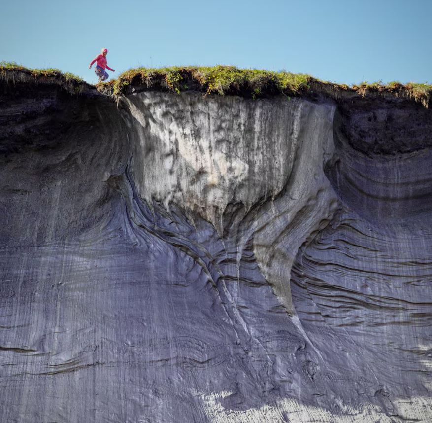 A woman walks along the top of a tall cliff edge