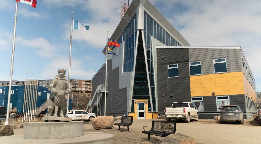 A building is seen with flags outside and a sculpture.