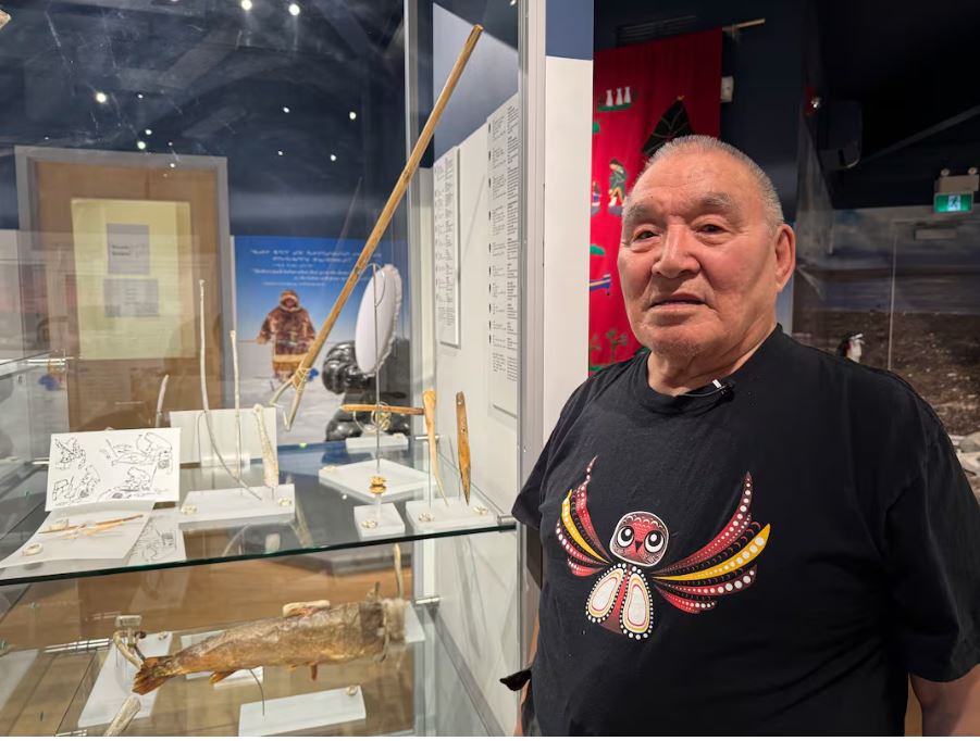man stands next to cabinet, with artifacts on display