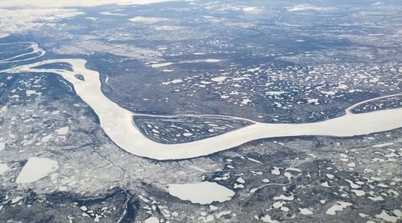 Aerial view of a white, frozen river winding through a snowy landscape.