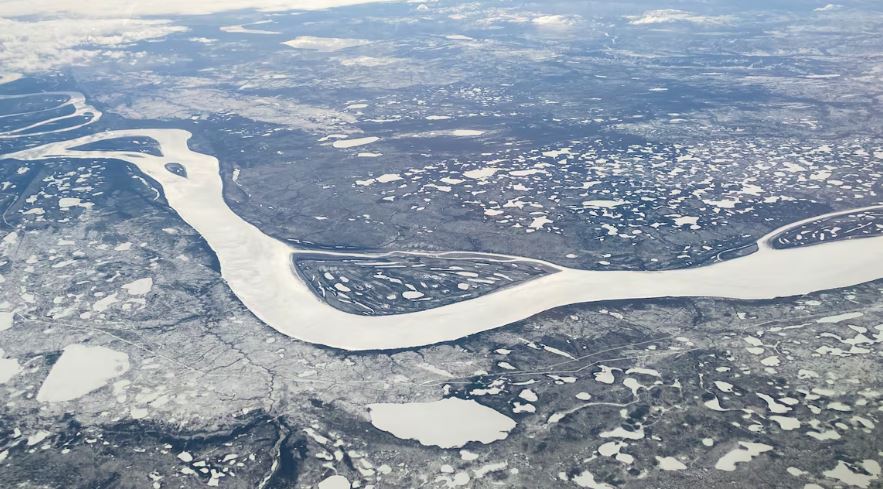 Aerial view of a white, frozen river winding through a snowy landscape.