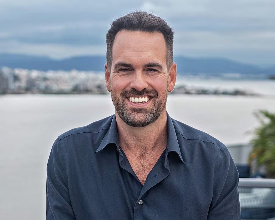 man in blue collar shirt stands on balcony