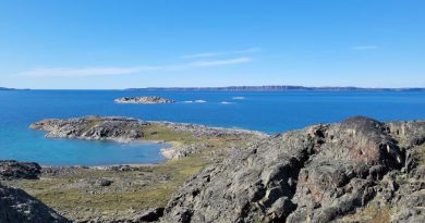 A rugged rocky coast line with blue ocean in the background with more rugged coast behind