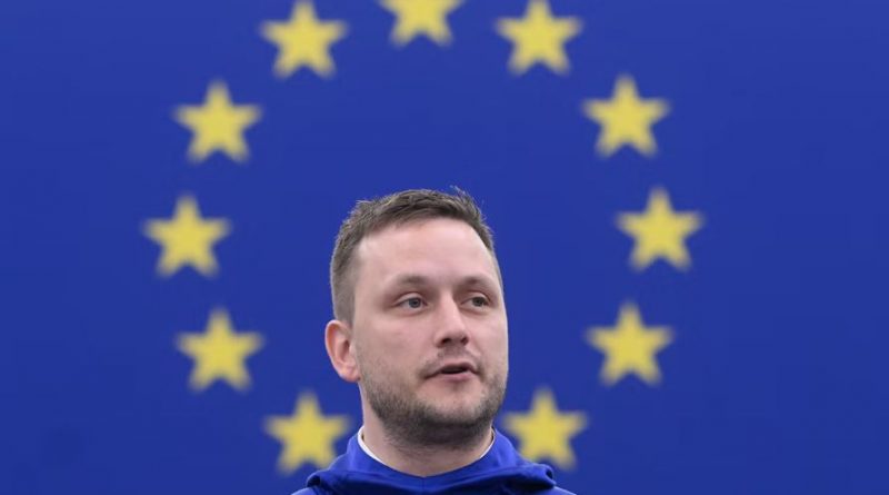 The Greenlandic prime minister speaks in front of an EU flag.