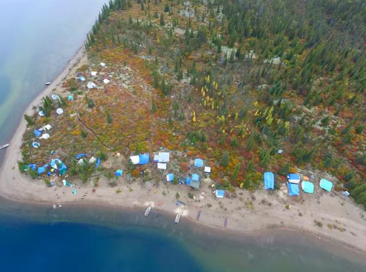A birds-eye view of a camp set near the shores of a body of water.