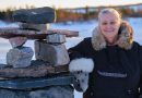 A woman smiles next to a pile of stones.