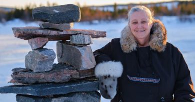 A woman smiles next to a pile of stones.