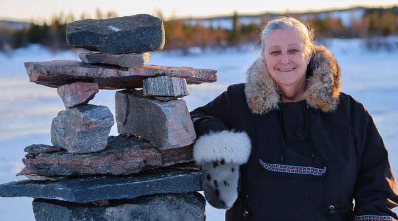 A woman smiles next to a pile of stones.