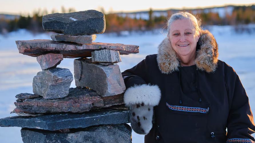 A woman smiles next to a pile of stones.