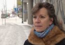 A woman stands on a city sidewalk in winter.