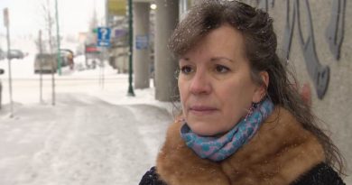 A woman stands on a city sidewalk in winter.