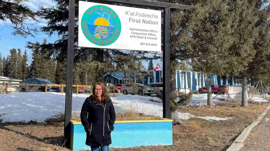 A woman standing in front of a sign looking at the camera.