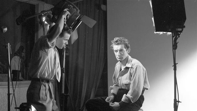 Félix Leclerc, auteur-compositeur-interprète (Sur la photo est aussi présent Gaby ajustant l'éclairage) (Vers 1951) - Ronald Desmarais/Gaby, collections BAnQ