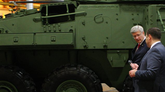 Le premier ministre Stephen Harper, lors d'une visite à l'usine de General Dynamics, en mai 2014. Le véhicule blindé léger qu'on peut y voir était destiné au gouvernement canadien et non à l'Arabie saoudite. Photo : PC/Dave Chidley