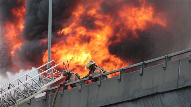 Des pompiers combattent l’incendie sur l’autoroute métropolitaine. Photo Credit: Facebook/Brigitte Hébert-Carle 