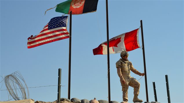 Un soldat canadien s’apprête le 11 mars 2014 à mettre le drapeau canadien en berne à la base de Zangabad, en Aghanistan, lors du retrait des forces canadiennes de Kandahar (archives).