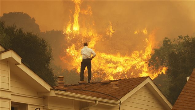 Un Canadien en 2017 regarde le feu s’approcher de sa maison. Les feux de forêt plus fréquents sont l’un des phénomènes que l’on associe au réchauffement climatique.Photo Credit: David McNew/Getty Images RCI avec La Presse canadienne et Radio-Canada 