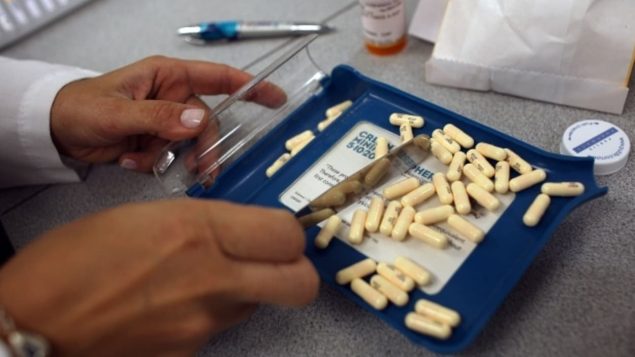 Des mains de pharmaciens trient des pilules - Photo : Radio-Canada
