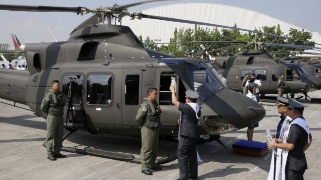 Un aumônier militaire philippin asperge d'eau bénite, en 2015, un des huit appareils alors acquis de Bell Helicopter. Photo : The Associated Press/Bullit Marquez