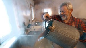 À la cabane du Pic Bois, au Québec, la famille Pollender fabrique le sirop d'érable dans la plus grande tradition. Affairé autour de son évaporateur, André Pollender, le propriétaire de la cabane. Photo : Radio-Canada