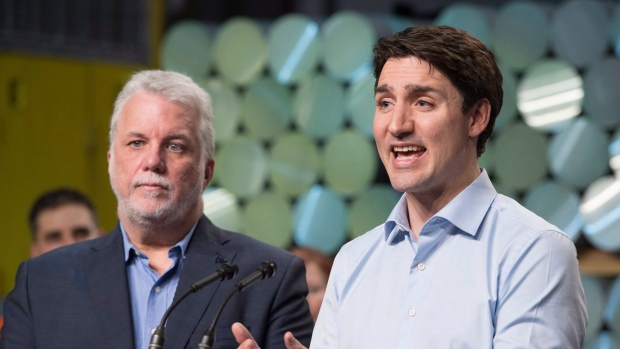 Le premier ministre du Québec, Philippe Couillard, regarde le premier ministre Justin Trudeau s'adresser aux travailleurs et aux journalistes lors d'une conférence de presse lors d'une visite de l'usine d'aluminium Rio, le lundi 12 mars 2018 à Saguenay au Québec. (Jacques Boissinot / Presse canadienne)