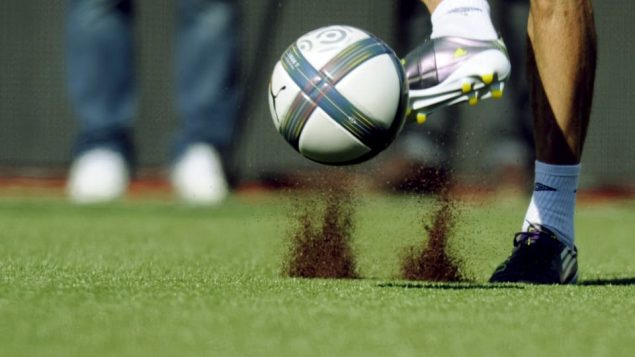 Des particules de caouthouc volent dans les airs lorsqu'un joeur de soccer frappe un ballon.