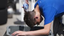 A fire pit crew member dumps water on his head to get relief from the heat wave during the the practice session at the Honda Indy in Toronto